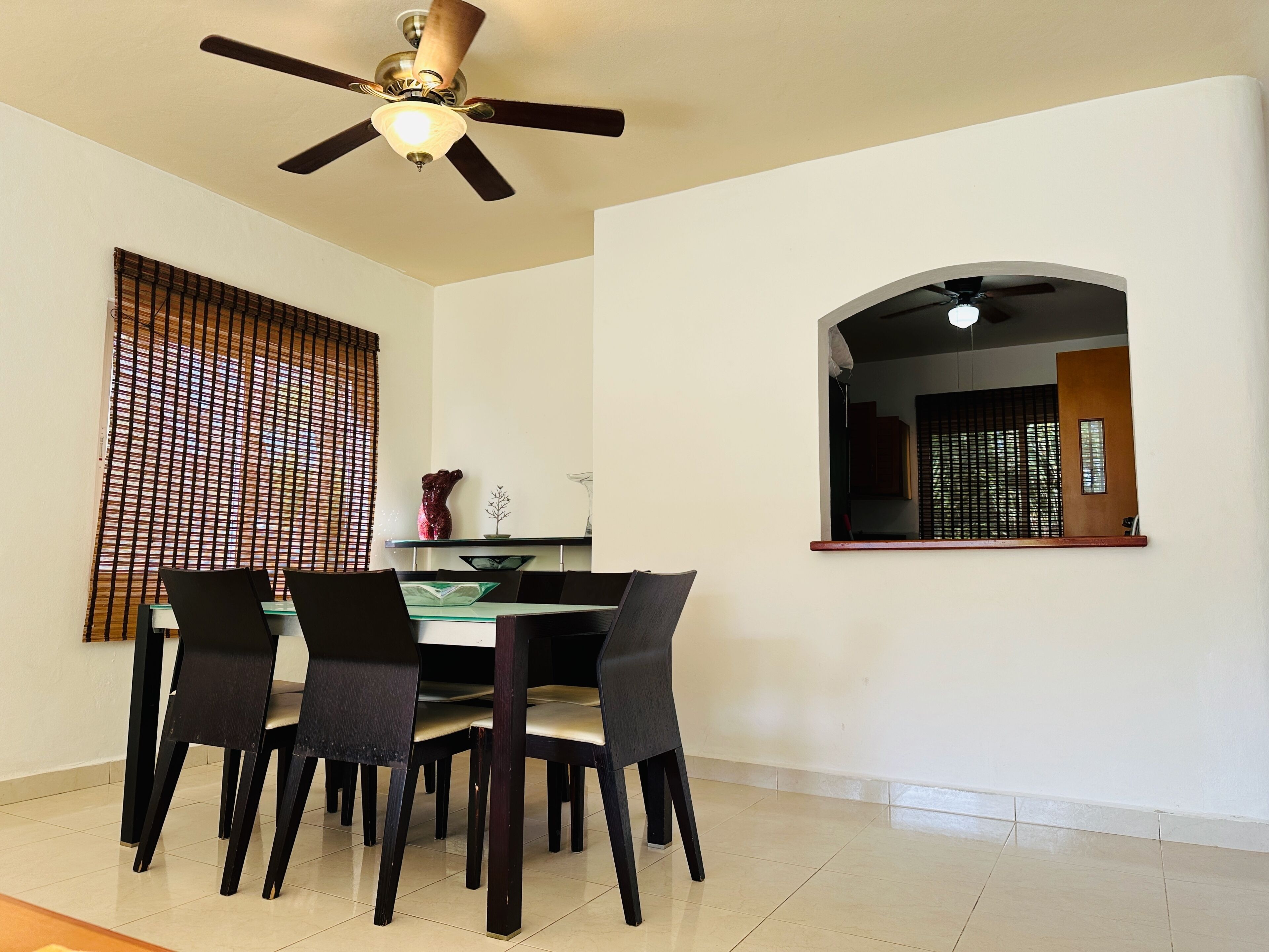 A dining area with a table and chairs, a ceiling fan, and a window with blinds.