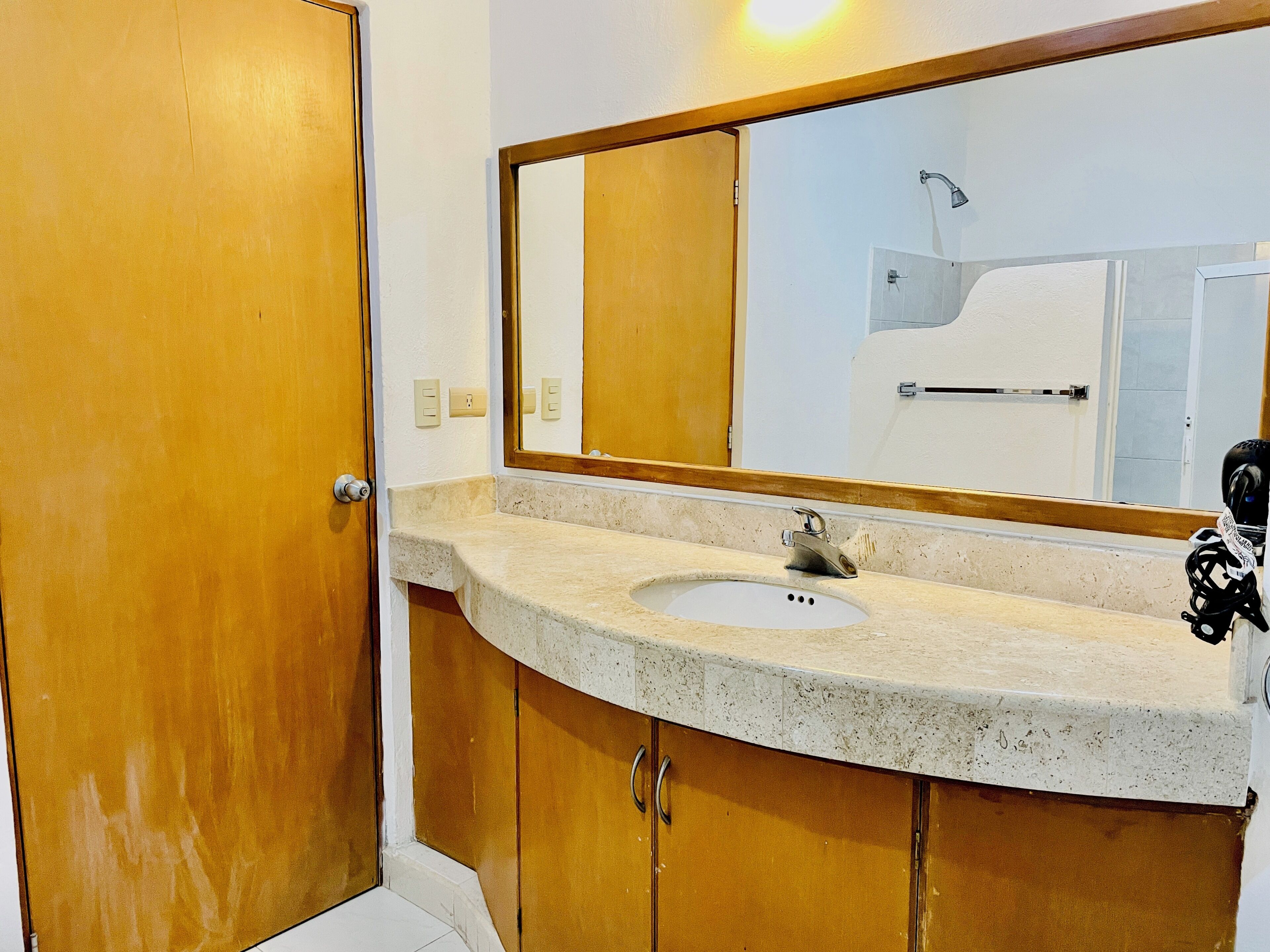 A bathroom with a wooden door, a sink with a faucet, and a mirror above the sink.