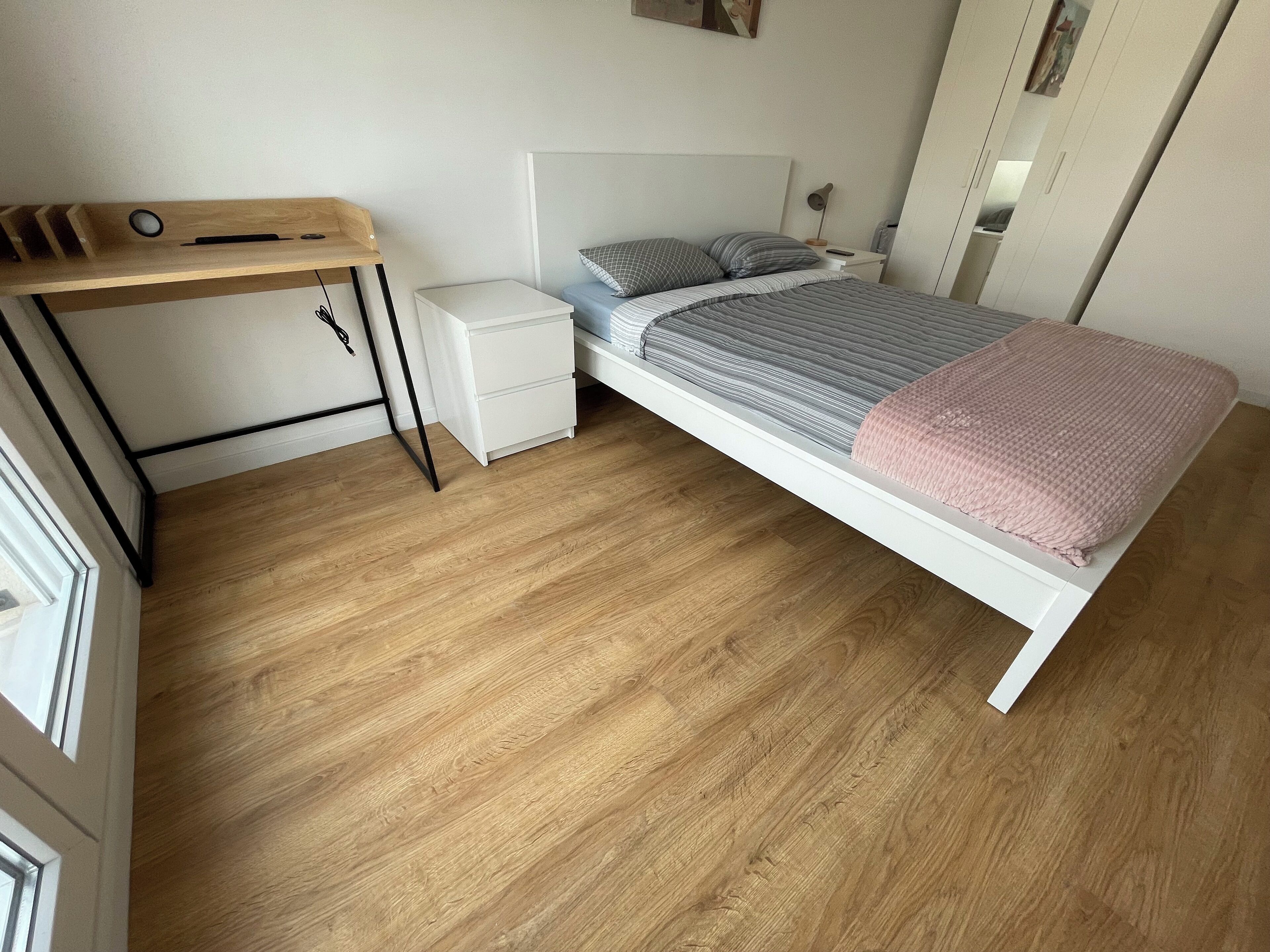 Ein Schlafzimmer mit Bett, Schreibtisch, Nachttisch und Kleiderschrank.