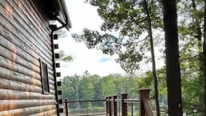 A wooden deck with a railing, leading to a cabin with a log exterior. - Premium Lakefront Log Cabin ~ORV (West Branch)