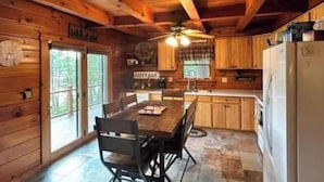 A wooden cabin interior with a dining area, kitchen, and a sign that reads "COTTAGE". - Premium Lakefront Log Cabin ~ORV (West Branch)