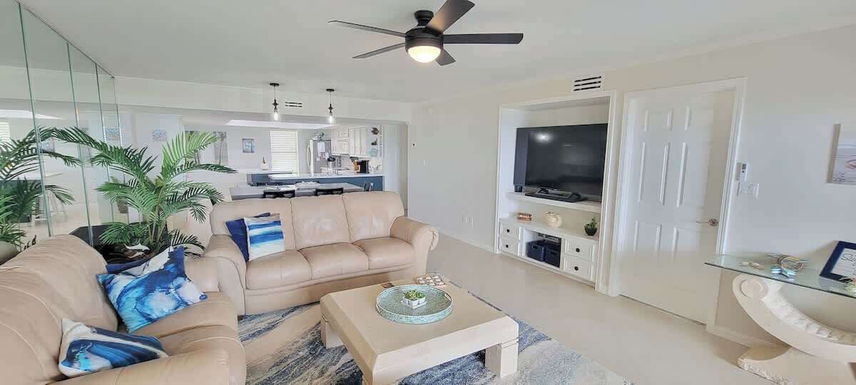 Een moderne woonkamer met een beige bank, een glazen salontafel en een flatscreen televisie.