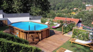 A wooden deck with a hot tub, lounge chairs, and a view of a forested hillside. - Maison d une Chambre Pour 4 Personnes (Arouca)