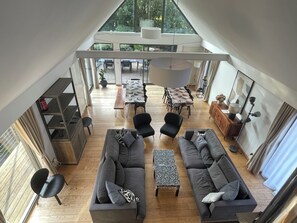 Un amplio espacio habitable con un sofá grande, una mesa de comedor y vistas al exterior a través de grandes ventanales.