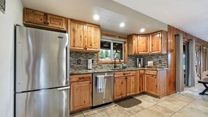 Una cucina moderna con mobili in legno, elettrodomestici in acciaio inossidabile e zoccolo a mosaico.