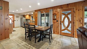 Un'ampia cucina con mobili in legno, un tavolo da pranzo con sedie e un'ampia porta in legno con una finestra circolare.