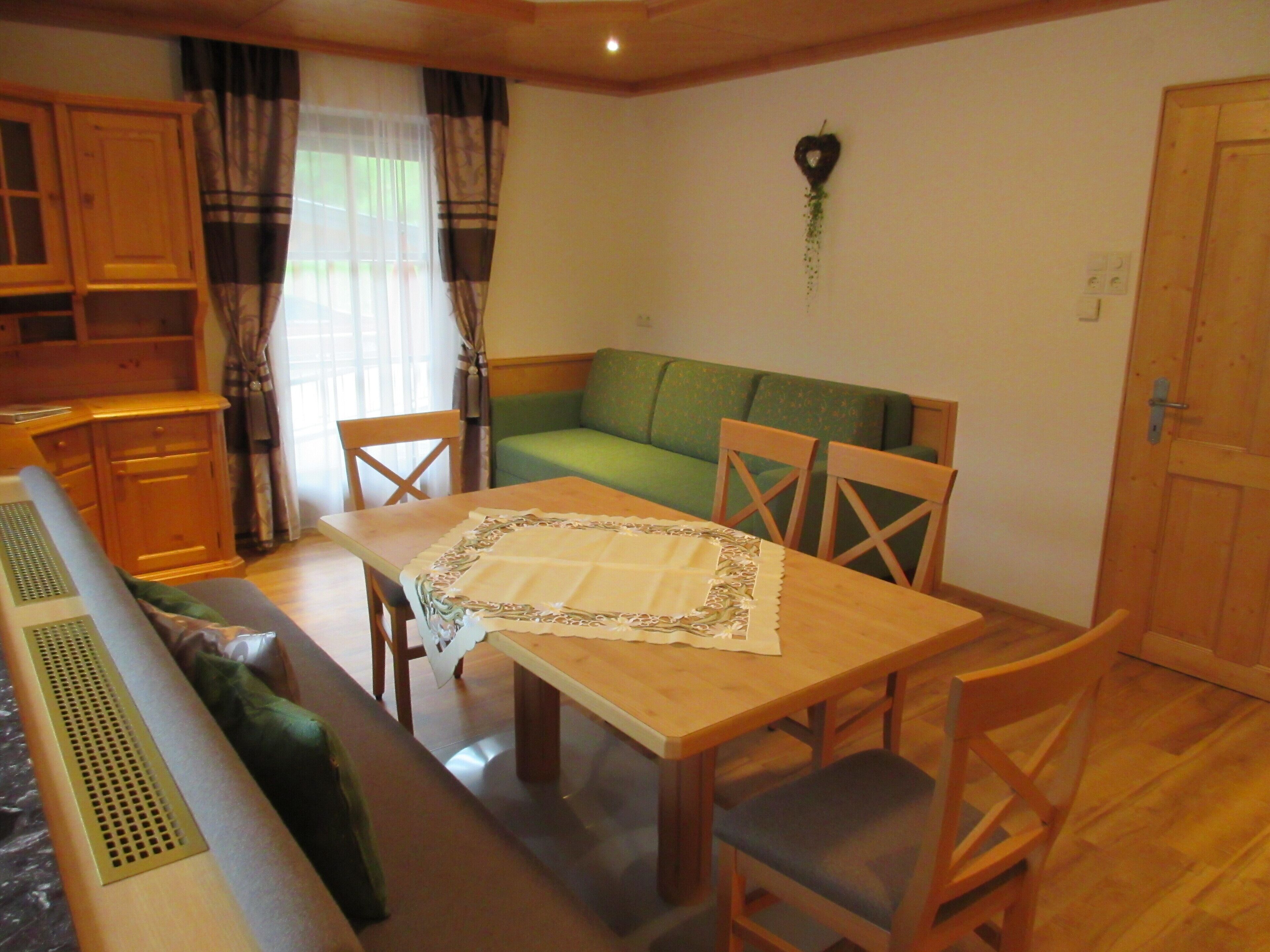 Un comedor acogedor con una mesa de madera, sillas y un sofá verde.