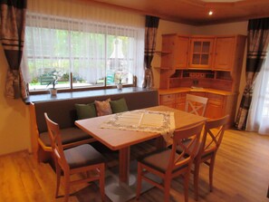 A cozy dining area with a wooden table and chairs, a bench, and a window with curtains.