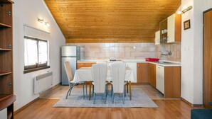 A compact kitchen with a wooden ceiling, a refrigerator, a sink, and a dining area with chairs and a table. - Nice apartment in Sibenik with WiFi (Sibenik)