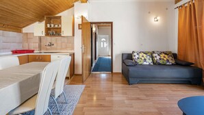 A compact living space with a kitchenette, a dining area, and a sofa with floral cushions. - Nice apartment in Sibenik with WiFi (Sibenik)