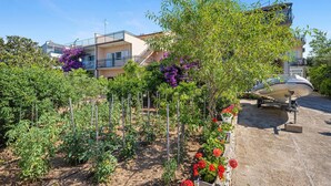 A residential area with a garden, a boat, and a building with balconies. - Nice apartment in Sibenik with WiFi (Sibenik)