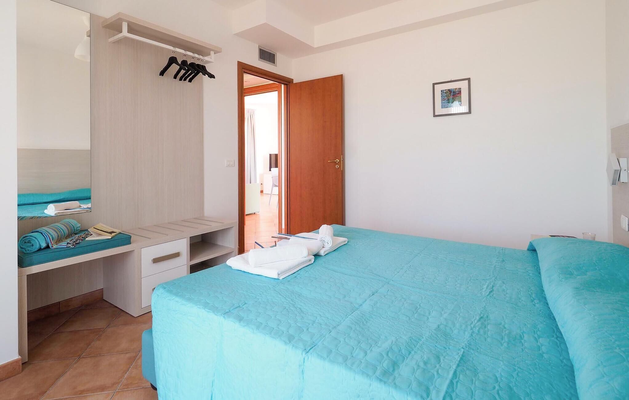 A bedroom with a bed, a desk, and a wardrobe.