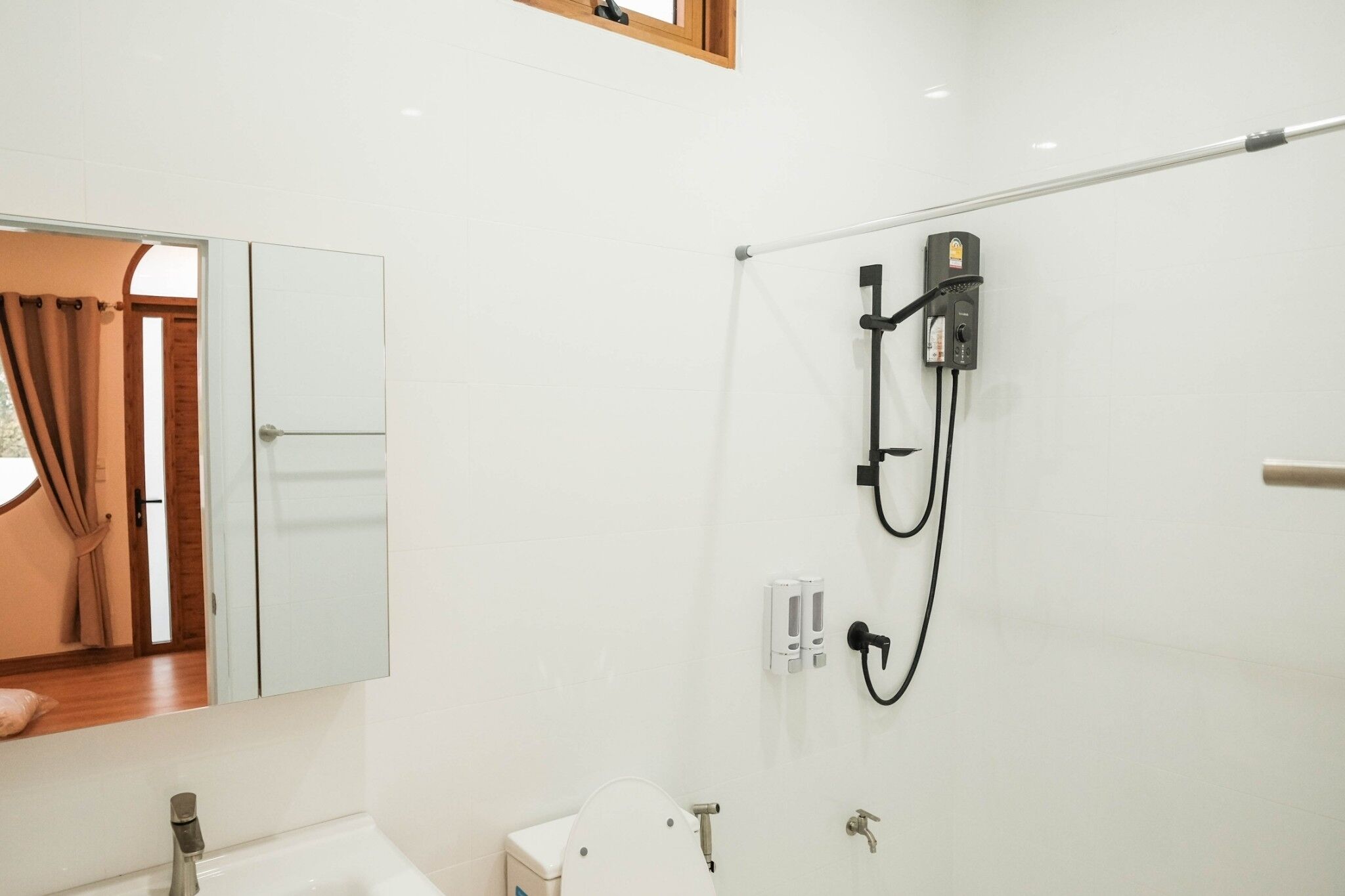 Ein Badezimmer mit Dusche, Toilette, Waschbecken und Spiegel.