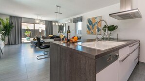 A modern kitchen with a central island, stainless steel appliances, and a dining area with a sofa and chairs. - Luxurious home in Biograd (Biograd)