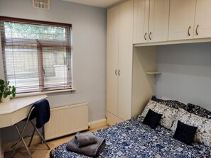 A bedroom with a bed, a desk, and a radiator.