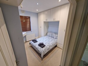 Un dormitorio con cama, radiador y ventana con persianas.
