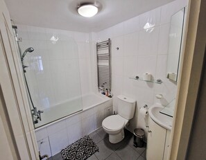 A bathroom with a glass-enclosed shower, a white toilet, a bathtub, a sink, and a mirror.