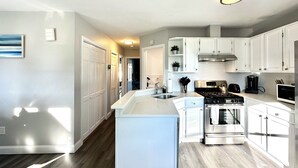 A modern kitchen with white cabinetry, stainless steel appliances, and a central island. - Beachy Getaway Near Newport & Beaches (Middletown)
