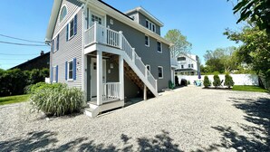 A two-story house with a front porch, a staircase, and a gravel driveway. - Beachy Getaway Near Newport & Beaches (Middletown)