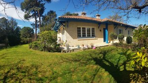A house with a tiled roof, a blue door, and a well-maintained garden with various potted plants.