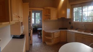 A compact kitchen with wooden cabinets, a white countertop, and a window providing natural light.