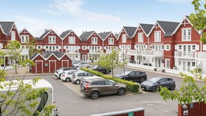 A row of red and white buildings with a parking area in front.