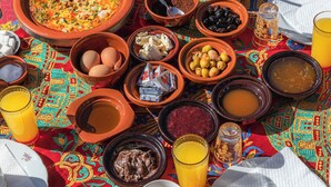 Un esmorzar marroquí tradicional amb diversos plats i begudes sobre un mantell de taula colorit.