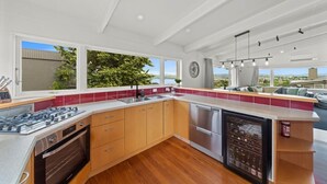 A modern kitchen with a large island, stainless steel appliances, and a view of the outdoors. - Hilltop House Lake Views (Taupo)