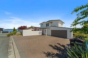 A modern two-story house with a garage, paved driveway, and a mailbox labeled "NO JUNK MAIL".