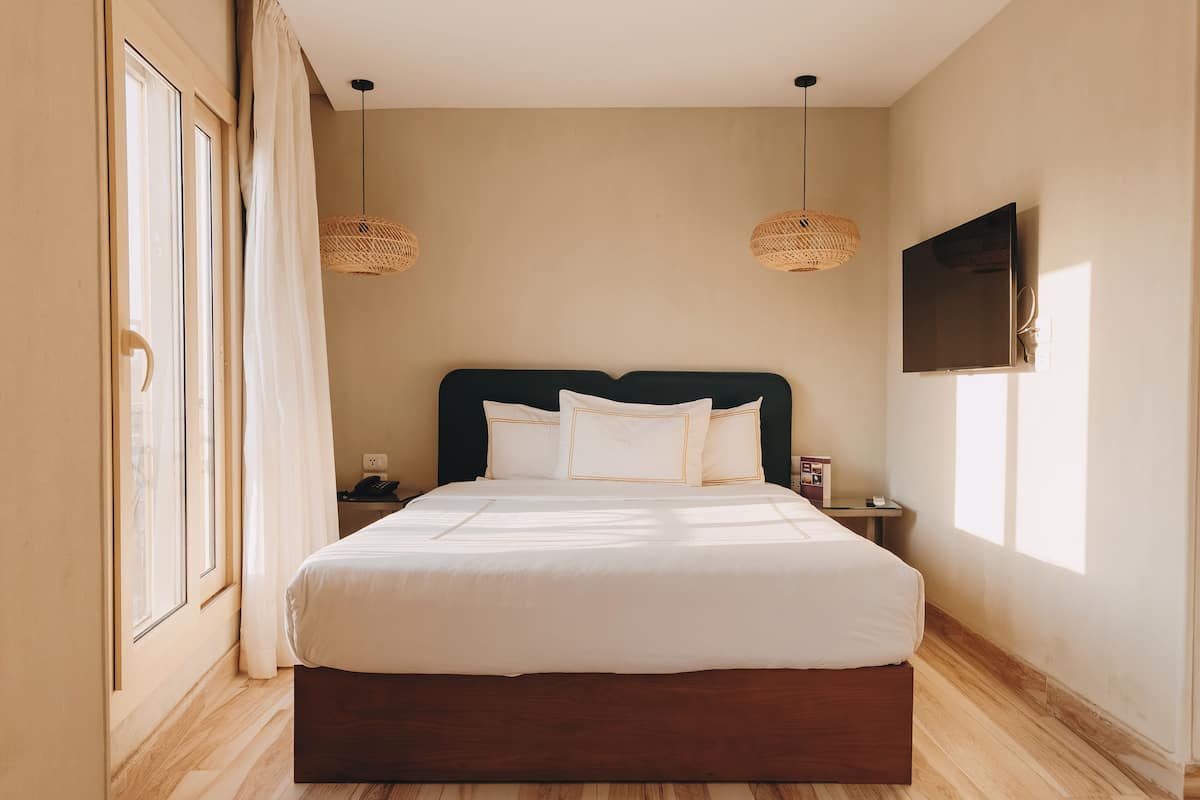 A neatly made bed with white linens, a dark headboard, and two bedside lamps.