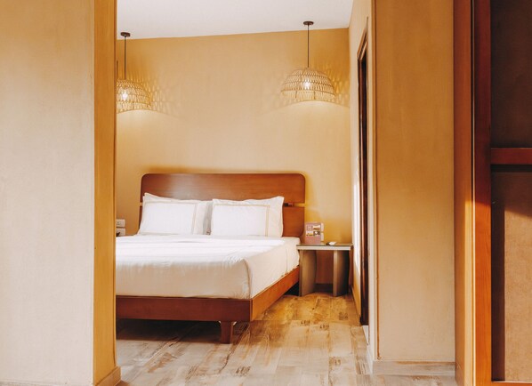 A hotel room with a wooden bed, two bedside lamps, a nightstand, and a door leading to another room. - Almas Pyramids View (Giza)