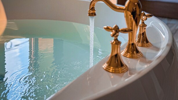 A bathtub with gold fixtures in a hotel room. - Almas Pyramids View (Giza)
