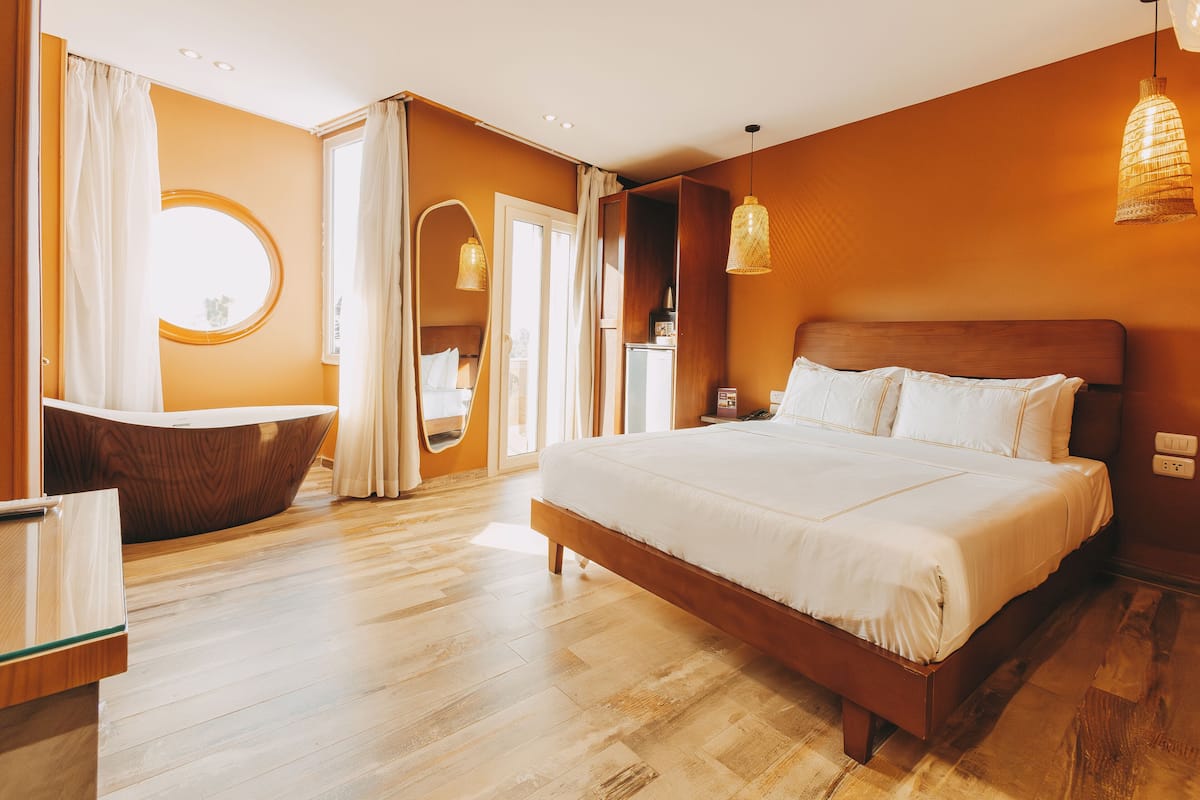 A modern bedroom with a large bed, a wooden vanity, and a round mirror.
