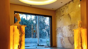A modern interior with a large window, a stone wall, and a seating area with a bench. - Almas Pyramids View (Giza)