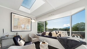 Een moderne woonkamer met een groot raam, een kaart aan de muur en een gezellige zithoek.