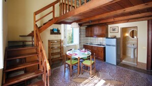 A wooden staircase leading to a second floor, a kitchen with wooden cabinets, a dining table with chairs, and a sink. - Eucalipti 2 - Apartment (Porto Azzurro)