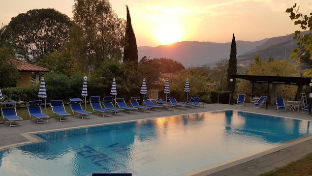 A swimming pool with lounge chairs and umbrellas, surrounded by trees and hills. - Eucalipti 2 - Apartment (Porto Azzurro)