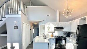A modern kitchen with white cabinetry, a black refrigerator, and a central island.
