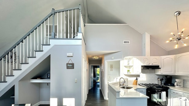 A modern kitchen with white cabinetry, a central island, and a staircase with white railings.