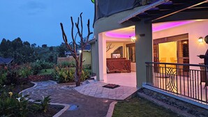 A residential property with a paved garden pathway leading to a balcony with a railing. - Kaije Country Cottages (Fort Portal)