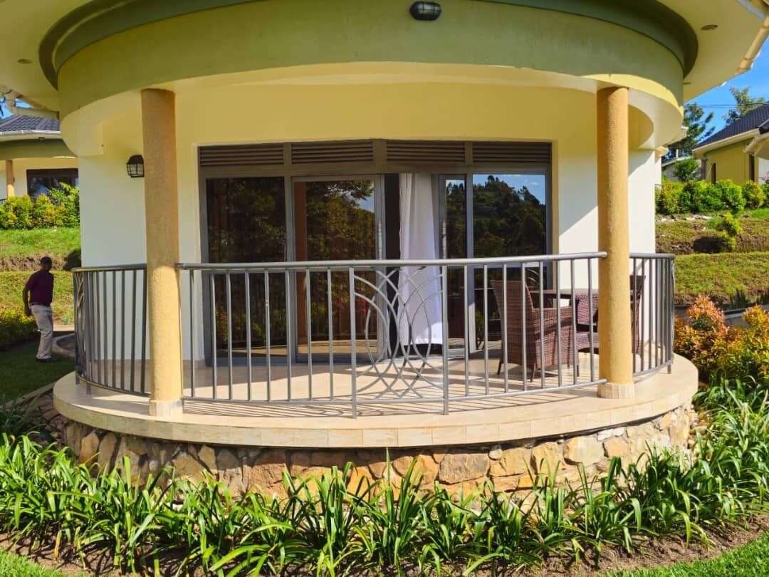 A covered outdoor area with a circular design, featuring a railing and a seating area with a table and chairs.