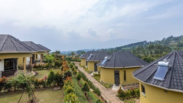 A row of yellow buildings with dark roofs, arranged in a linear fashion with a central pathway. - Kaije Country Cottages (Fort Portal)