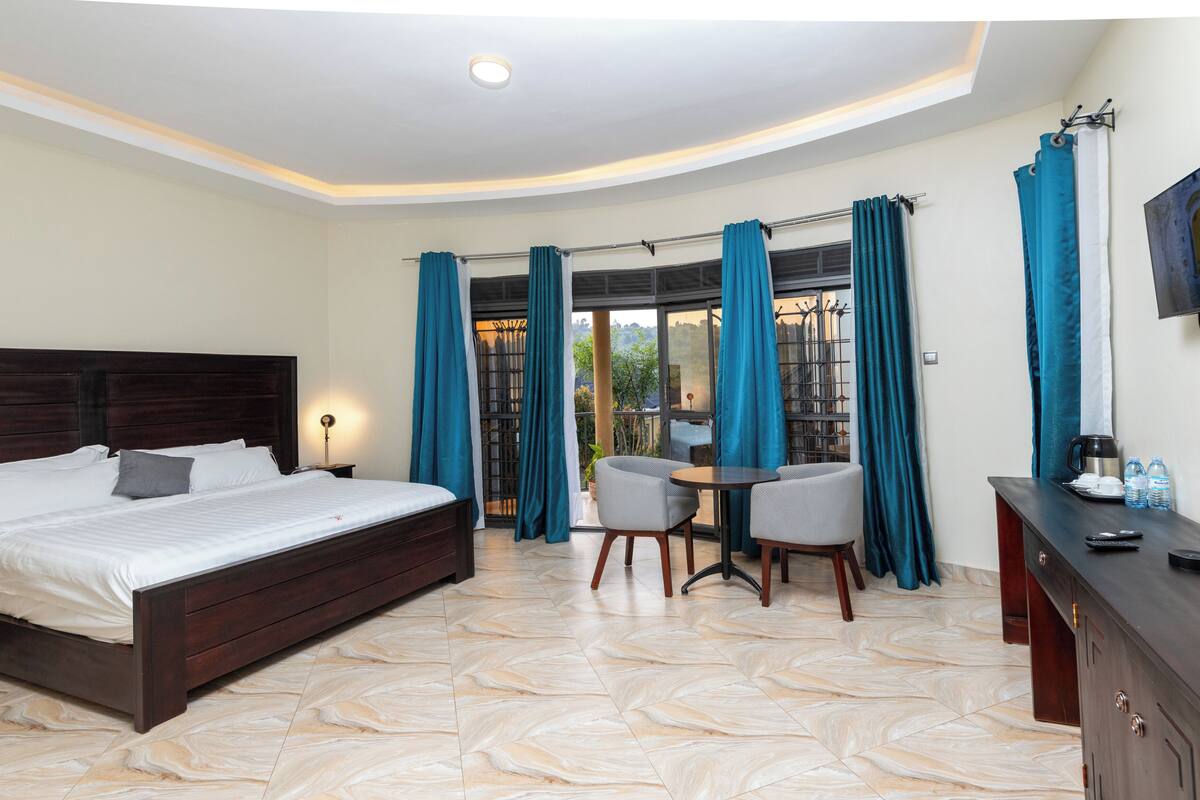 A bedroom with a bed, a desk, and a chair. There is a window with curtains.