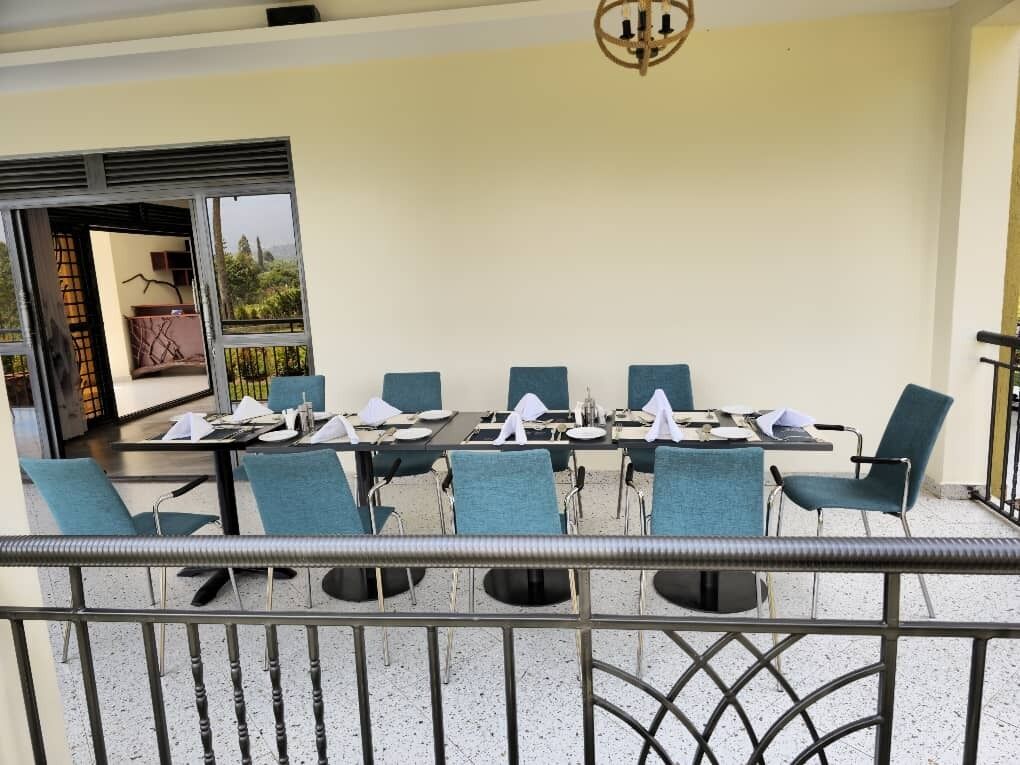A dining area with a table set for six, blue chairs, and a balcony railing.