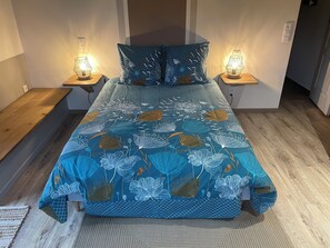 A bedroom with a floral bedspread, two bedside lamps, a wooden bench, and a textured rug.