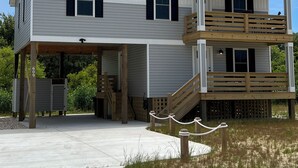 A two-story house with a covered porch and a wooden deck. - Sound Views! Brand New 3 bedroom (Kill Devil Hills)