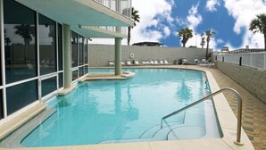 A swimming pool with a sun deck, lounge chairs, and a view of palm trees. - 7th Floor Beachfront Complex 2 BR 2B Beautifully furnished wFree Beach Service  (Fort Walton Beach)