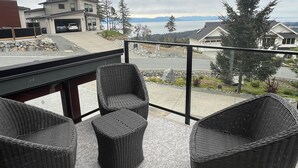 Un balcon doté de meubles en osier, donnant sur un quartier résidentiel et un plan d’eau.
