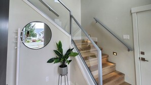 Un escalier moderne avec des rampes en verre, une plante en pot et des œuvres d’art accrochées aux murs.