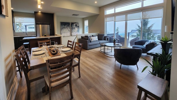 Un espace de vie moderne comprenant un coin repas, un canapé et un balcon doté de grandes fenêtres.